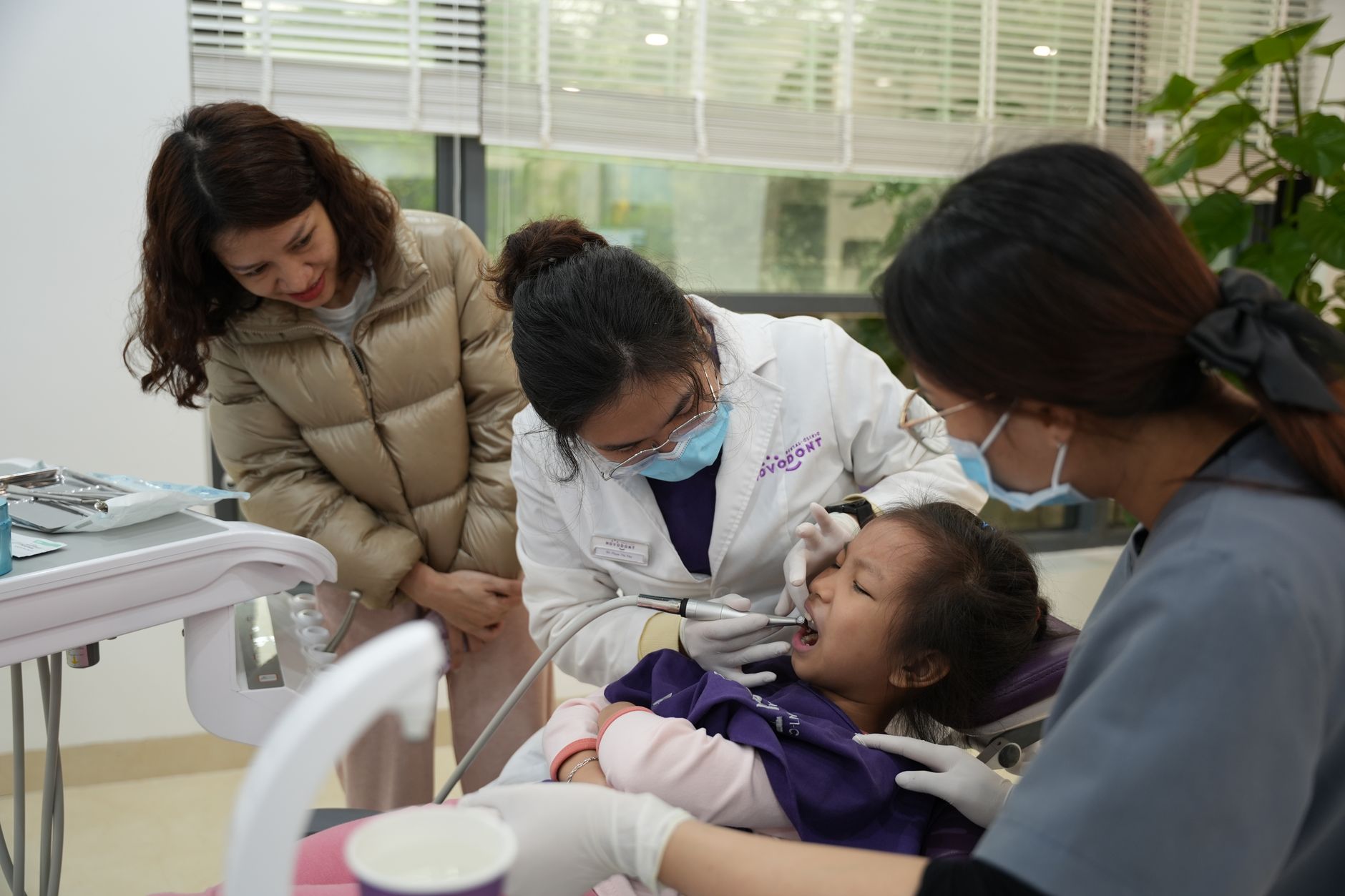 Tout-petit assis sur la chaise du dentiste pédiatrique pendant un examen doux avec un parent à ses côtés