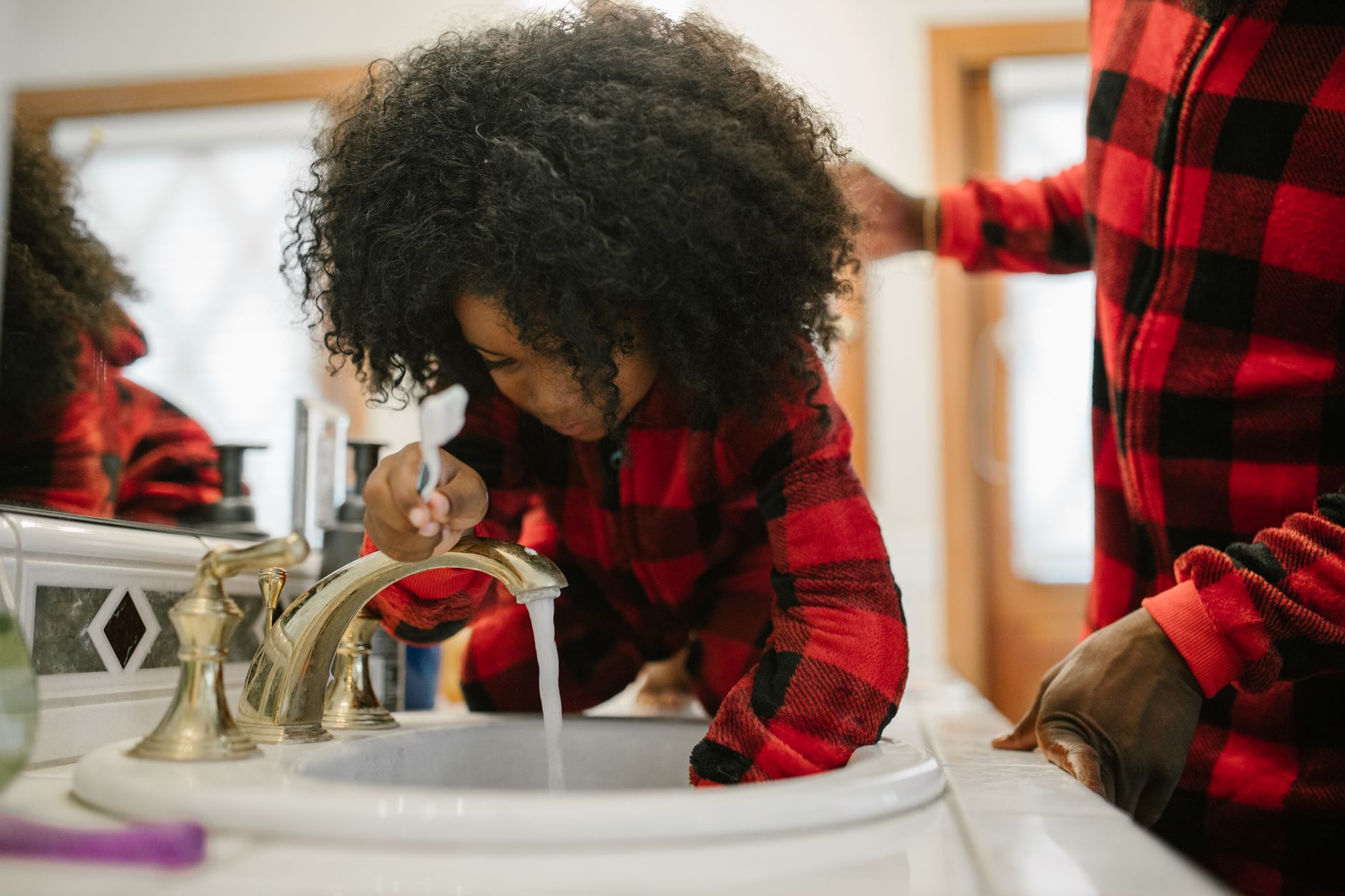 Parent qui brosse les dents de son jeune enfant pour prévenir la carie et bâtir de bonnes habitudes d'hygiène