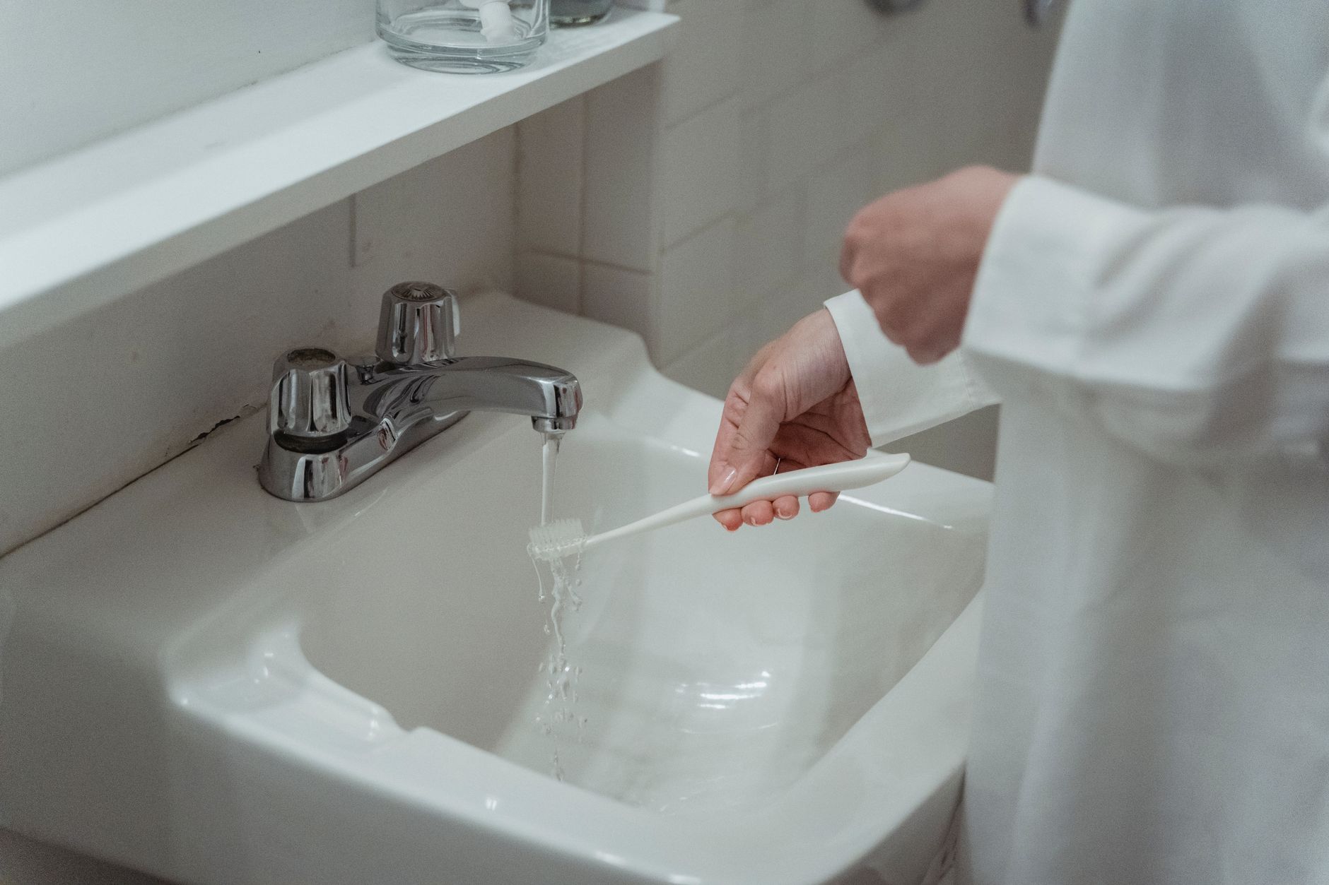 Entretien quotidien des prothèses dentaires avec brossage doux des prothèses au-dessus d'un lavabo pour éviter les rayures