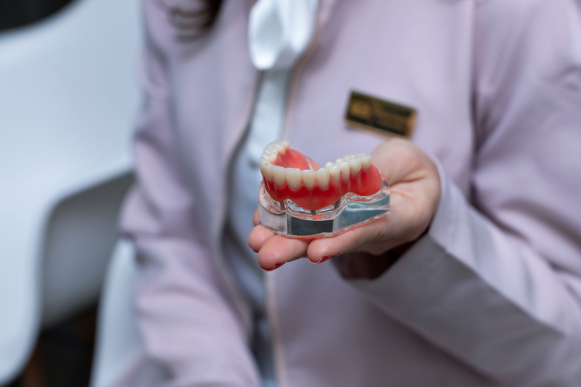 Dentiste tenant un modèle de prothèse complète pour expliquer l'ajustement et les soins quotidiens à un patient