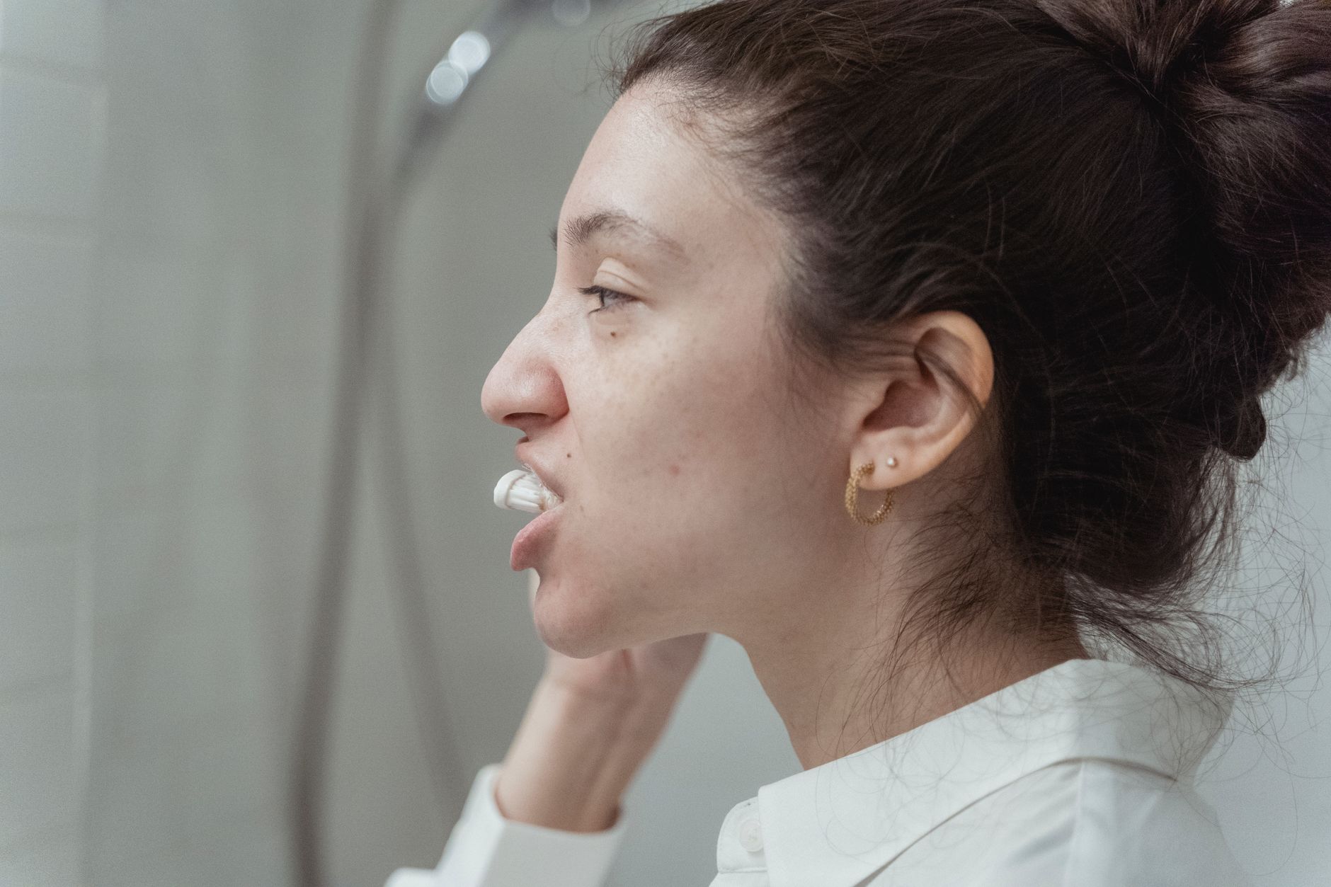 Person fitting a custom tray for teeth whitening at home in front of a bathroom mirror