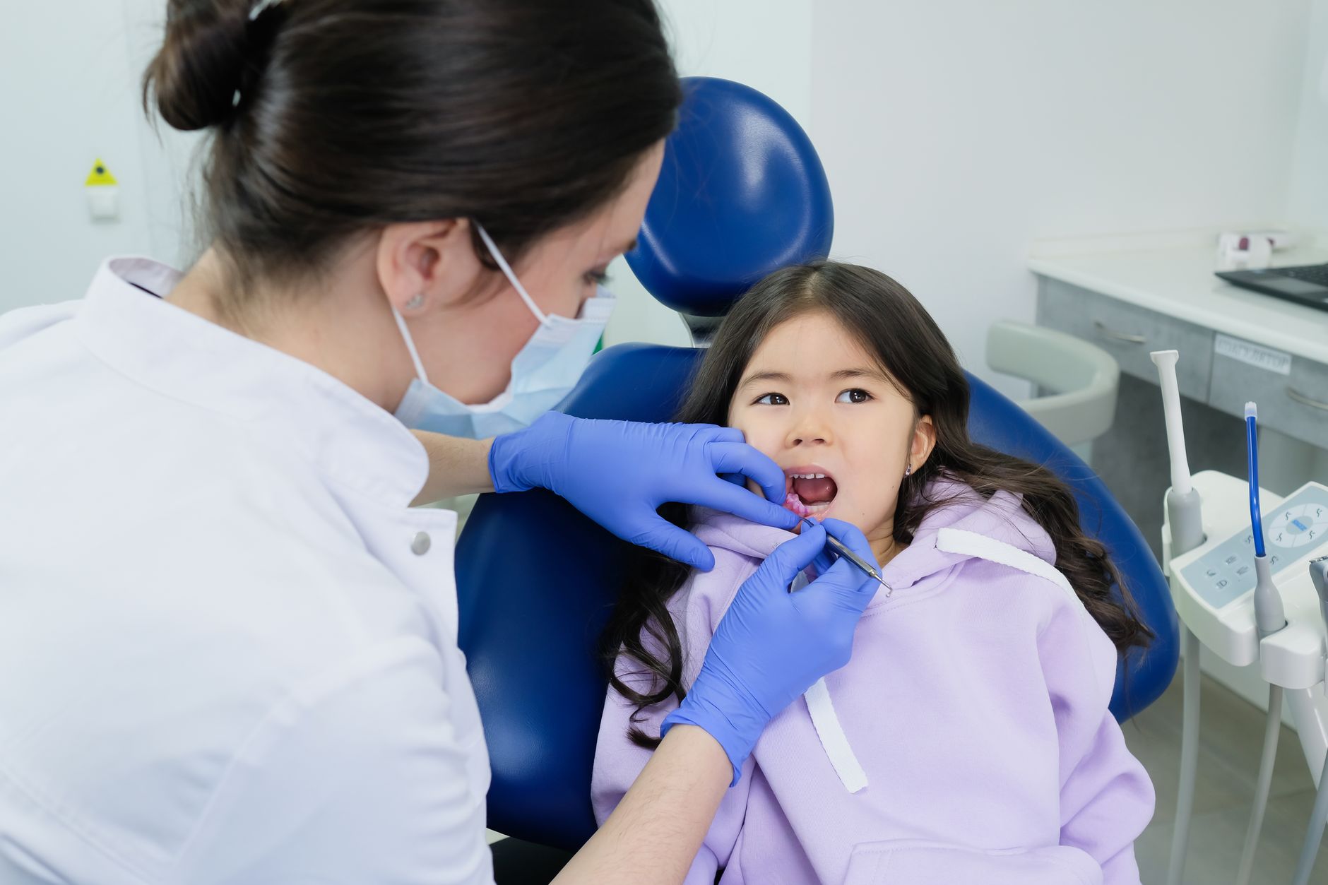 Young child smiling in a dental chair during a first dental visit in Sainte-Julie