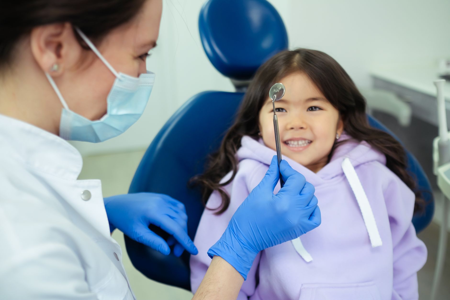 Friendly dentist showing tools to a curious child to ease kids dental anxiety at a first checkup