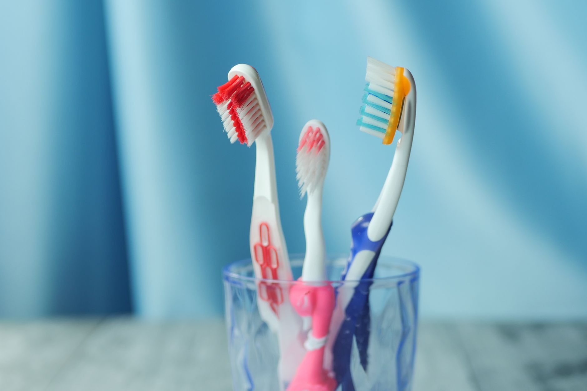 Close up of bleeding gums showing a pink toothbrush right after brushing the teeth