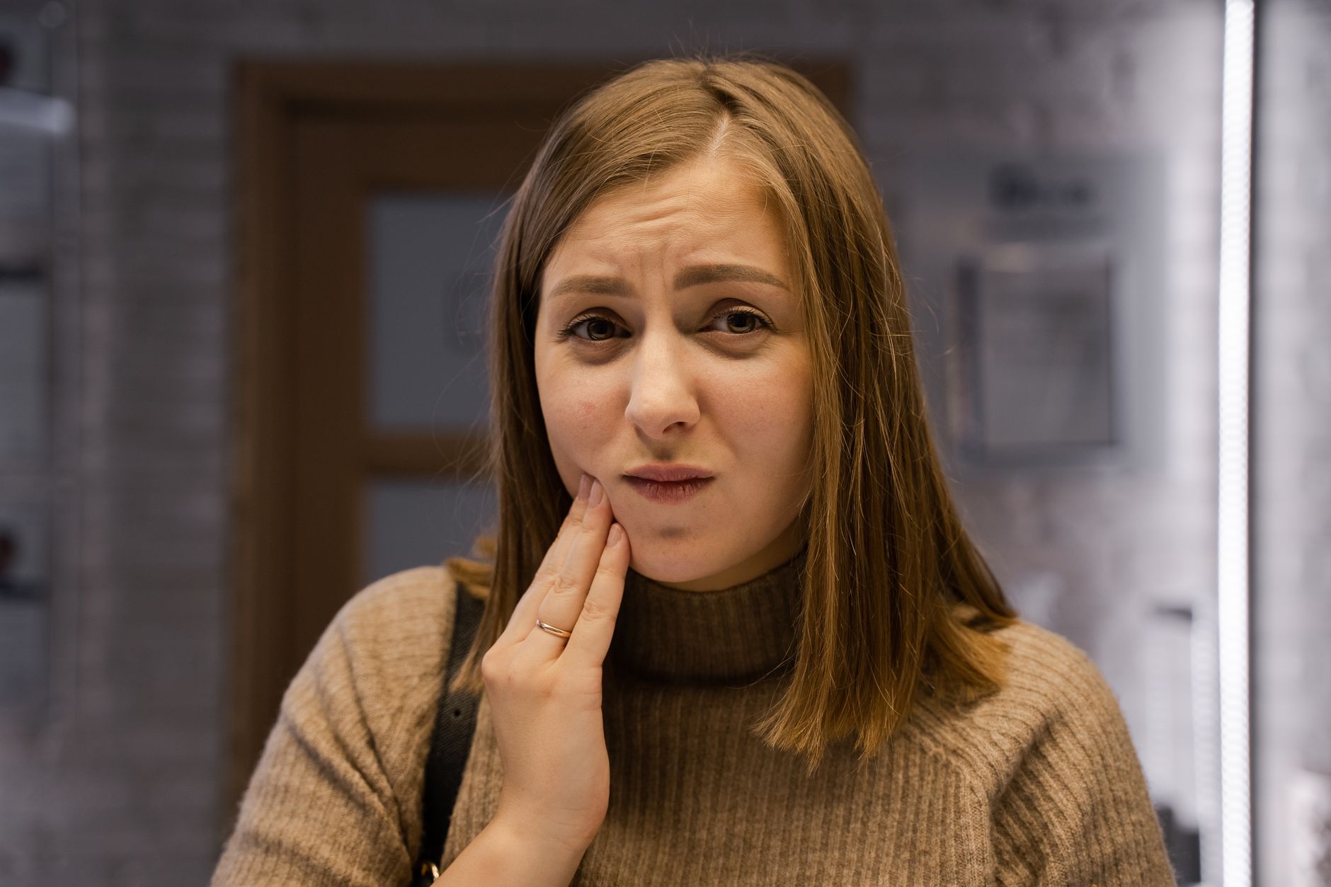 Woman holding her cheek at night from a toothache seeking toothache remedies to ease the pain