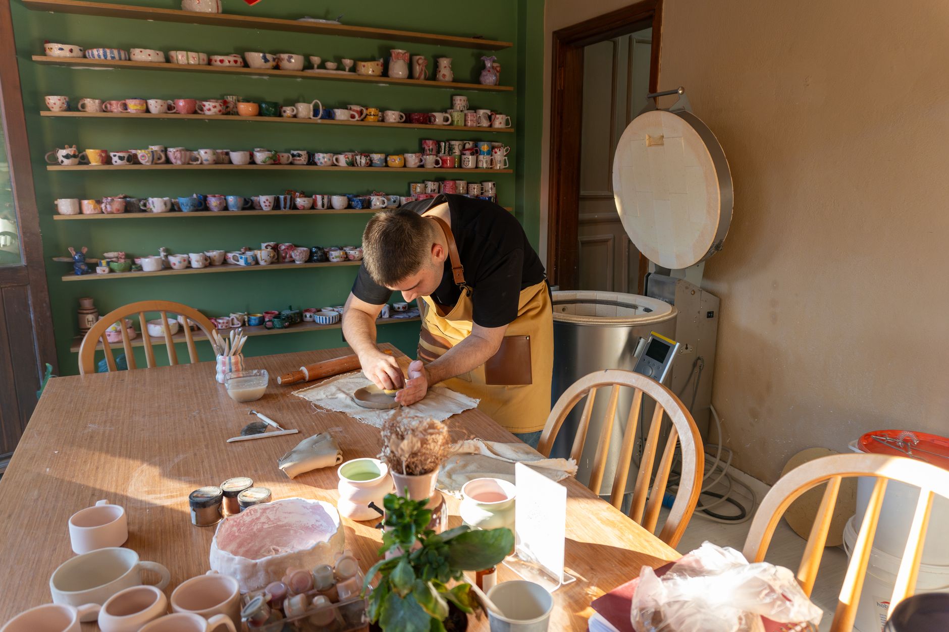 Jeune couple riant pendant un atelier de poterie, fabriquant des tasses ensemble.